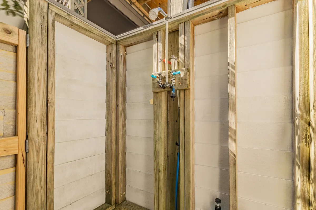 An open, invigorating outdoor shower with wooden framing and modern fixtures, suggesting a refreshing rinse after sandy beach adventures.